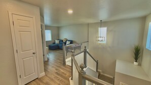 A hallway leading to a living area with a staircase, a door, and a window. - Modern Luxe Haven. Close to the airport, military bases, and downtown (Colorado Springs)
