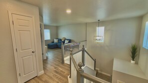 A hallway leading to a living area with a staircase, a door, and a window.