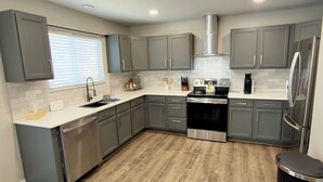 A modern kitchen with grey cabinets, a stainless steel stove, and a built-in oven. - Modern Luxe Haven. Close to the airport, military bases, and downtown (Colorado Springs)