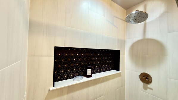 A modern bathroom with a geometric patterned wall, a built-in shelf with a bottle, and a shower head. - Modern Luxe Haven. Close to the airport, military bases, and downtown (Colorado Springs)