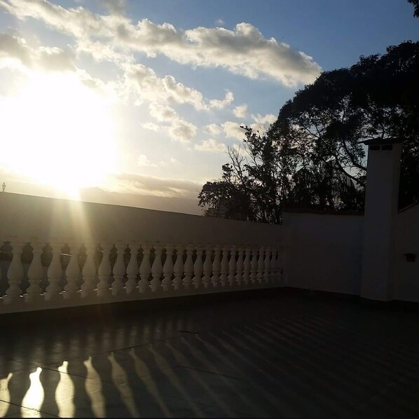 A balcony with a balustrade, a clear sky, and the sun setting or rising.