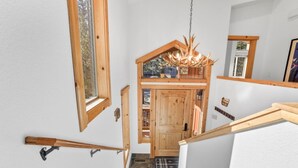 Una scala in legno con una porta in vetro che dà su una stanza con soffitto in legno e un lampadario.