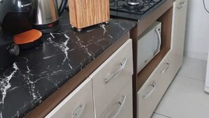 Eine Küche mit schwarzem Marmor-Arbeitsplatz, einem Gasherd, einer Kaffeemaschine und einem Messerblock.