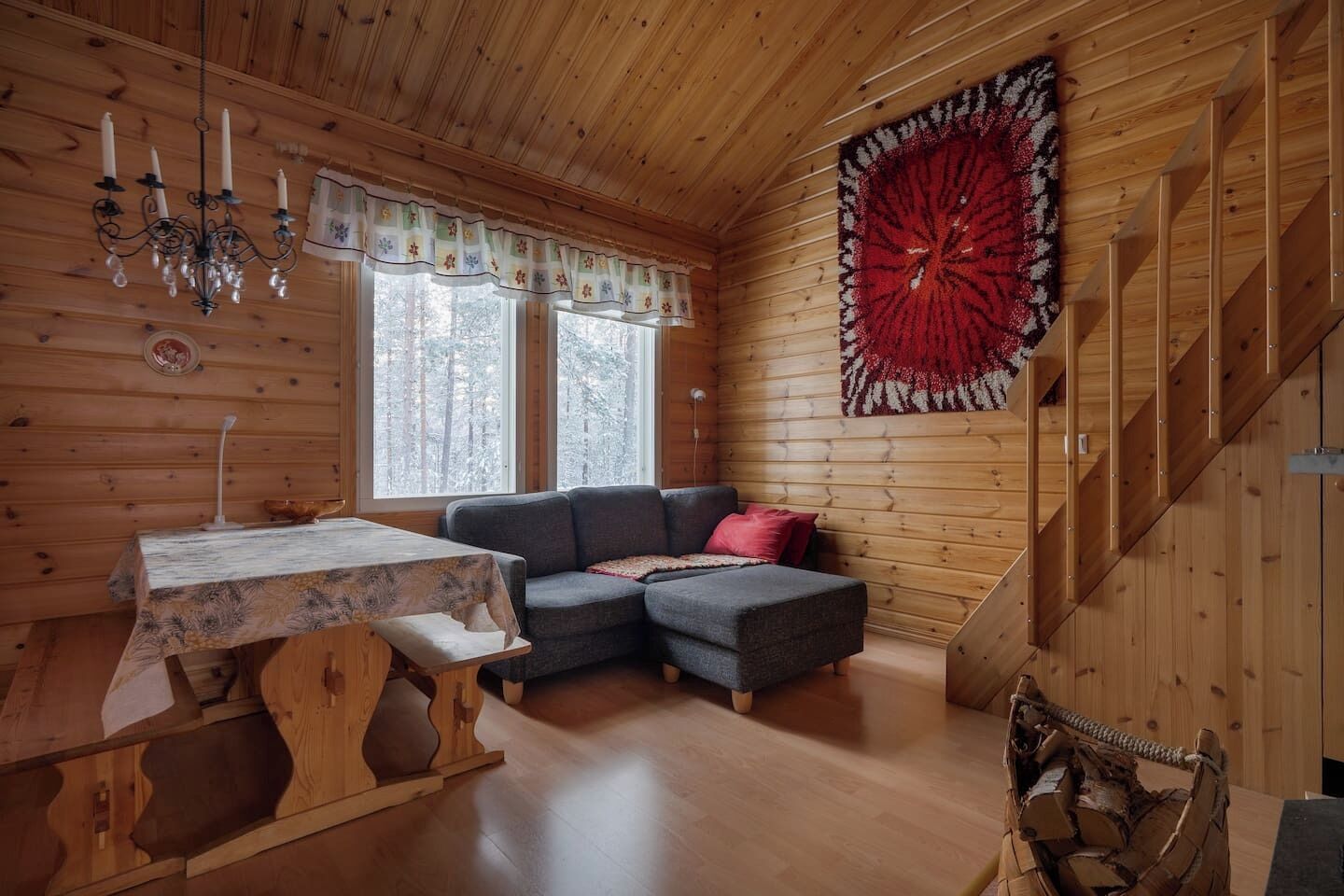 En mysig stuga med träpanel på väggarna, en soffa, ett bord och en stor matta.