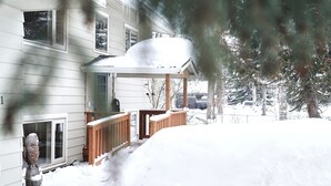 Ein zweistöckiges Haus mit einer überdachten Veranda und einem schnee bedeckten Vorgarten.