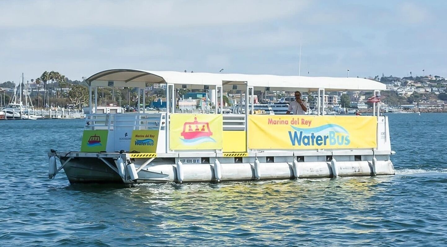 A water bus with a covered deck and advertisements for 'Marina del Rey WaterBus'.