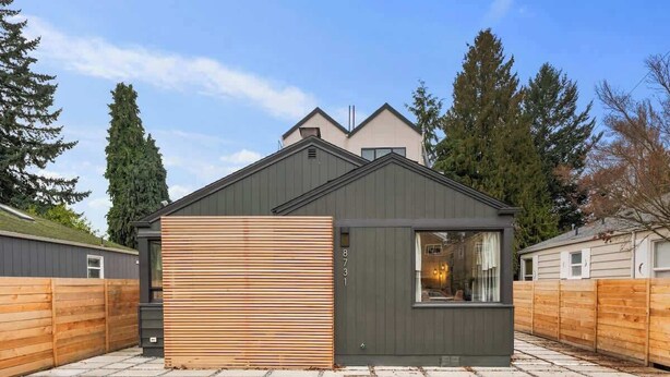 Un edificio moderno e compatto con tetto spiovente, facciata in legno e una piccola finestra.
