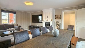 Un salon moderne avec une table à manger en bois, des canapés gris et un téléviseur à écran plat.