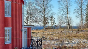 Un bâtiment rouge avec une porte et des fenêtres blanches, entouré d’un paysage enneigé et d’arbres.