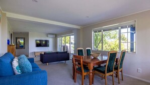 A spacious living area with a blue sofa, a dark-colored couch, and a wooden dining table with chairs.