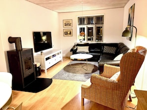 En stue med pejs, sofa, sofabord og en fletstol.
