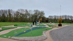 A golf course with a putting green, sand bunkers, and a flagstick.