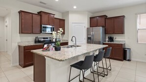 Eine moderne Küche mit Granit Arbeitsplatten, Edelstahlgeräten und dunklen Holzschränken.