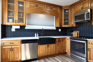 Una cocina con armarios de madera, lavavajillas, estufa y microondas.