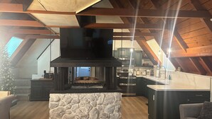 Eine moderne Küche mit Kamin aus Stein, Holzbalken und einer großen Kochinsel.