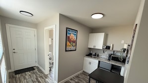 Una cocina funcional con armarios blancos, una encimera con lavabo y un pequeño comedor.