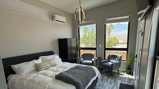 Un dormitorio con una cama grande, dos sillones, una mesita y vistas al exterior.