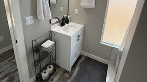 Un baño moderno con un lavamanos blanco, toallero negro y un espejo grande.