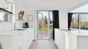 Une cuisine moderne avec des meubles blancs, un four encastré et une grande fenêtre.