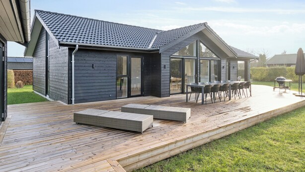 Une maison moderne dotée d’une terrasse, d’un espace salon extérieur et d’un coin barbecue.