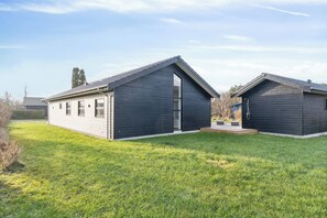 Una casa moderna de dos pisos con techo inclinado, ventanas amplias y un césped cuidado.