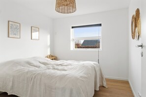 Un dormitorio con una cama grande, una ventana y una lámpara colgante.