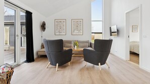 Un salon moderne comprenant un canapé, deux fauteuils, une table basse et un téléviseur.