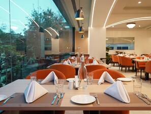 Un restaurante con mesas dispuestas para comer, que ofrece vistas a través de amplios ventanales.