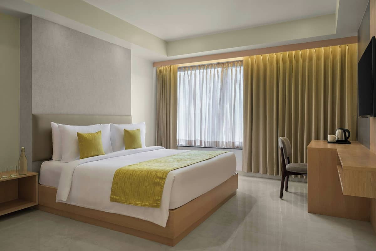Una habitación de hotel con una cama grande, un escritorio y una silla.