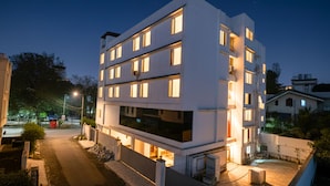 Um edifício moderno de vários andares com janelas iluminadas e portão fechado.