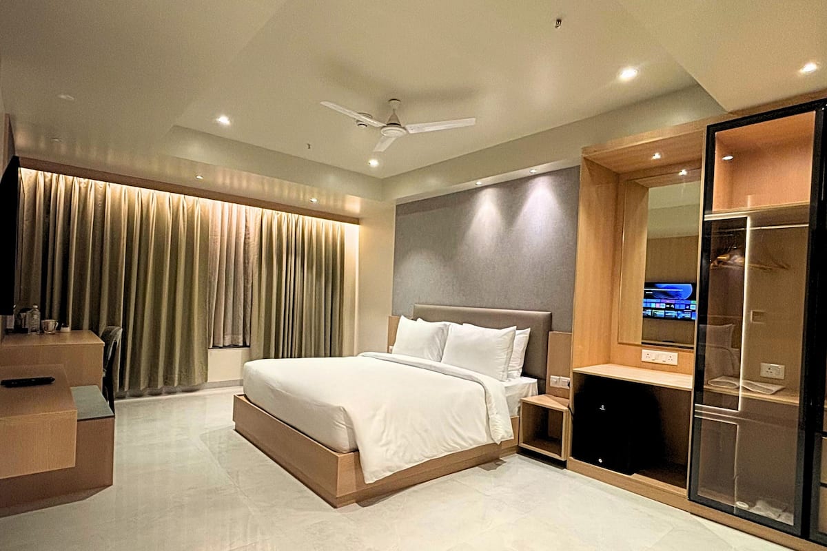Un dormitorio de hotel moderno con una cama grande, un televisor y un armario con puerta corredera.