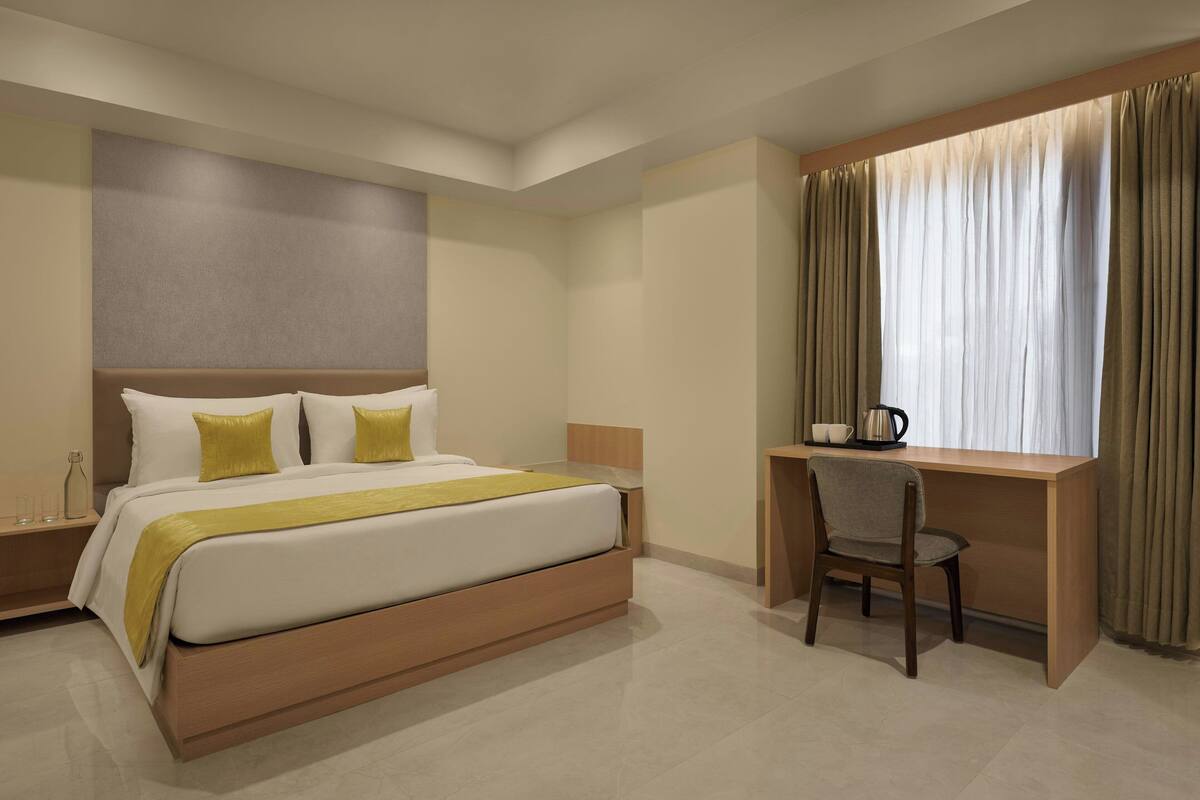 Una habitación de hotel moderna con una cama grande, un escritorio y una ventana con cortinas.