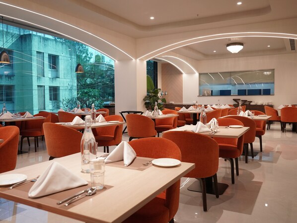 Un restaurante moderno con sillas y mesas naranjas, ventanas amplias y un interior limpio y bien iluminado.