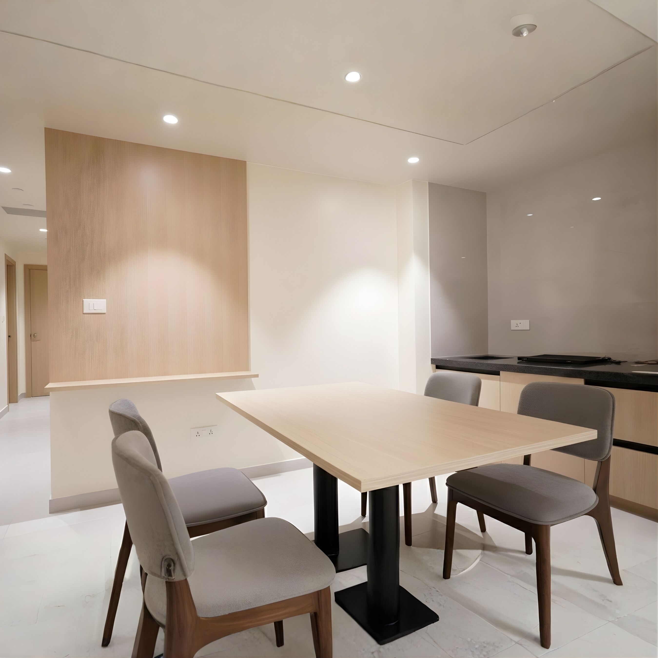 A modern dining area with a rectangular table, four chairs, and a kitchen in the background.