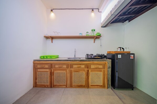 A compact kitchen with wooden cabinets, a sink, a gas stove, and a refrigerator.