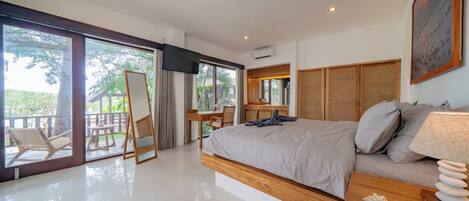 A modern bedroom with a large bed, a desk, and a view of the outdoors.