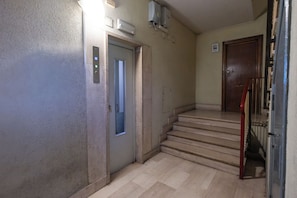 A hallway with a door, a staircase, and a wall-mounted air conditioning unit. - Marconi Urban House (Roma)