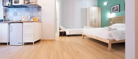 Una habitación pequeña con kitchenette, una cama y un armario.