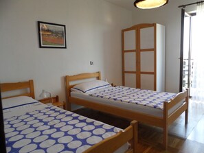 Una habitación con dos camas de madera, un armario de madera, un cuadro en la pared y una ventana con cortinas.