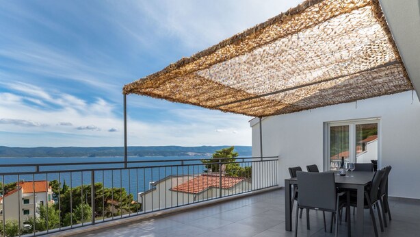 A balcony with a table and chairs, a view of the sea, and a pergola providing shade. - Apartman Irena by Interhome (Medici)