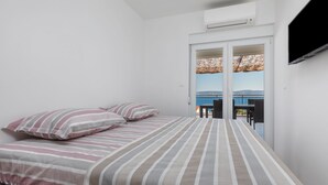 A bedroom with a bed, pillows, and a view of the outside balcony. - Apartman Irena by Interhome (Medici)
