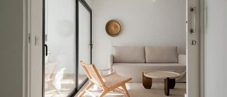 A modern living room with a sofa, a round coffee table, and two wooden chairs.