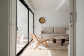 A modern living room with a sofa, a round coffee table, and two wooden chairs. - Sunny Oasis Apartment in La Oliva (La Oliva)