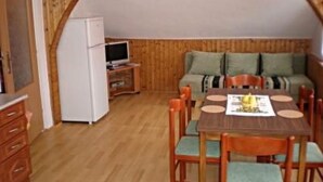A compact room with a wooden dining table, chairs, a sofa, and a small kitchenette area. - U SEMUSHKY Apartment 3 by Interhome (Pernink)