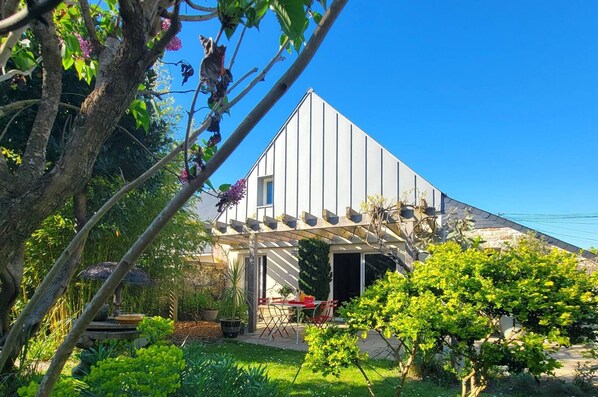 A modern house with a covered porch, a garden, and a clear blue sky. - Étel – 3-room house – 110 m² – WiFi - 3* (ETEL)