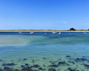A beach with clear water, boats, and a distant shoreline. - Étel – 3-room house – 110 m² – WiFi - 3* (ETEL)