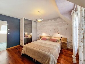 A bedroom with a large bed, a nightstand, a wall-mounted lamp, and a ceiling light. - Étel – 3-room house – 110 m² – WiFi - 3* (ETEL)