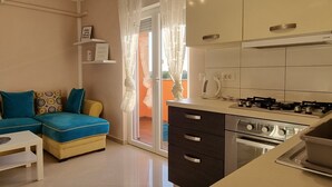 A compact living space with a kitchenette, a sofa, and a dining table.