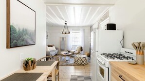A modern kitchen with a gas stove, white cabinets, and a dining area with a wooden table and chairs.