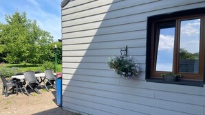 A building with a white exterior, a window with a brown frame, and a hanging flower basket. - Vallée des Prés by Interhome (Mesnil-Saint-Blaise)